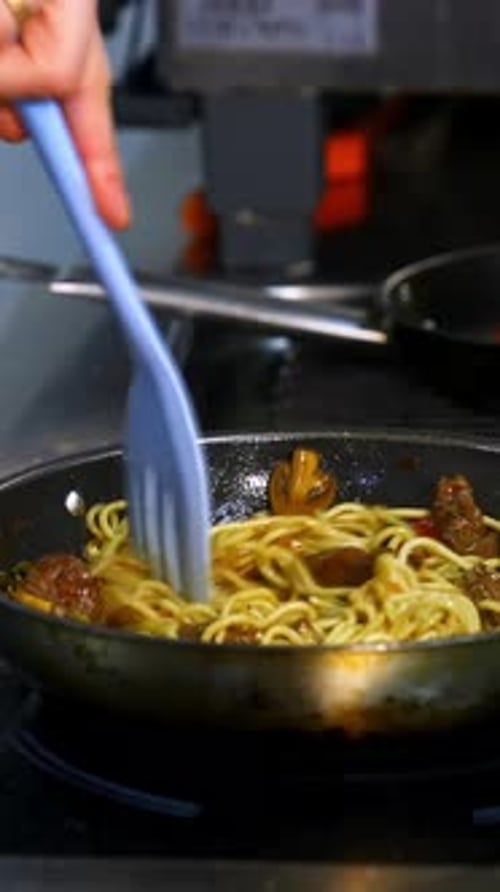Stirring Spaghetti with Meat and Vegetables in Skillet