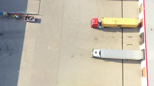 Lots of freight trailers. Cars are in several rows. Truck parking. Aerial view vertically down.