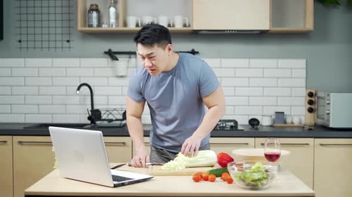 Hombre asiático preparándose en la cocina para un vídeo tutorial. Un hombre está viendo un tutorial de cocina