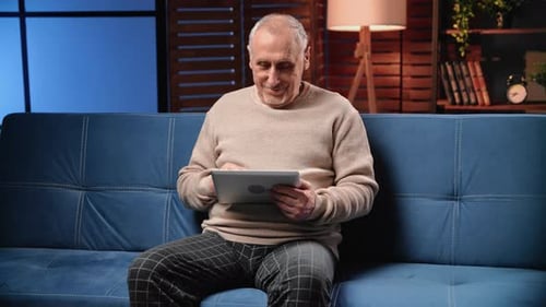 Cheerful Old Man Using Tablet for Communicating with Friends in Social Media Portrait in Home