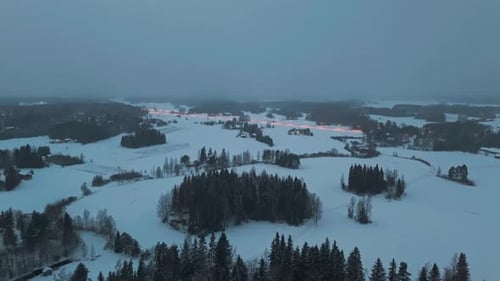 Flying over a dark ominous forest in Lapland wilderness woodlands. Approaching a road with lights se