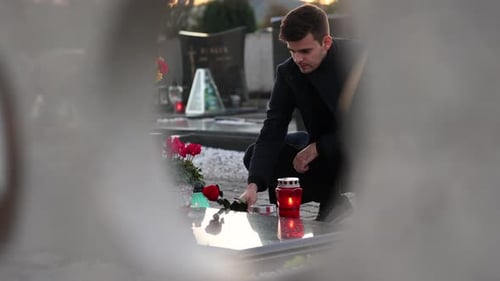 Man coming to the grave to place a flower on a graveyard. 4k footage