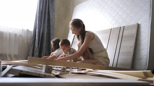 Young Single Mother with Kids Assembling Wooden Slats of an Orthopedic Base of a Double Bed
