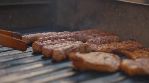 Outdoor Barbecue Cooking Meat On Grill With Tongs Close Up