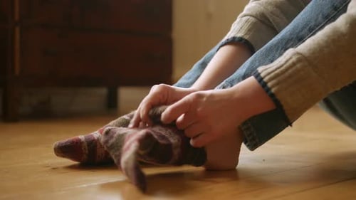 Person Putting on Striped Socks Indoors