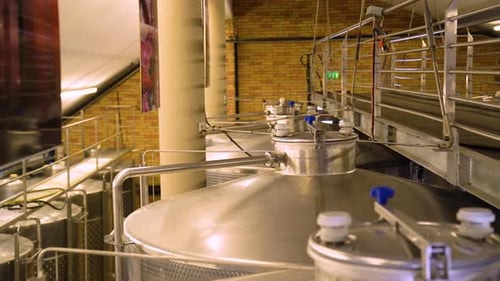 Panning View of Sealed Steel Containers in Winery Cellar with Industrial Bridge