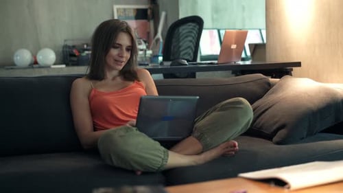 Woman Works on Laptop while Relaxing on Couch