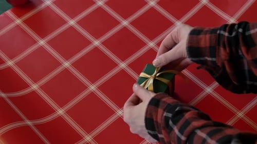 woman wrapping a Christmas gift box in colorful wrapping paper
