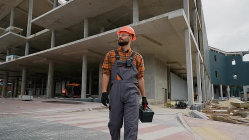Construction Worker Walking with Toolbox at Building Site
