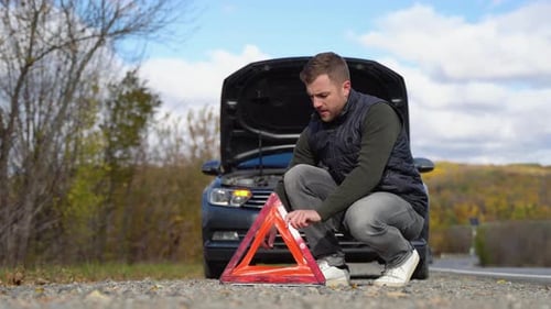 Young Man Puts It a Red Triangle to Warn Other Road Users Car Breakdown or Engine Failure Stop at