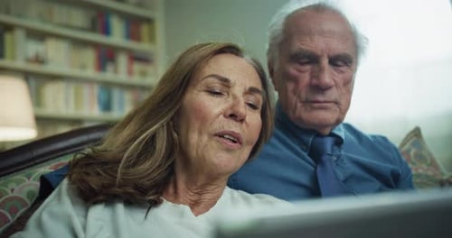 Cinematic shot of happy modern mature senior couple is using a tablet for family entertainment whi