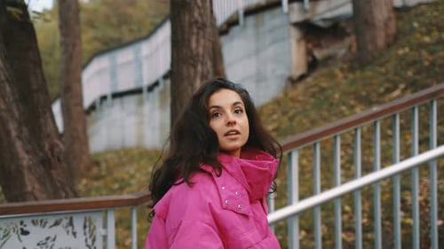 Young Woman in Stylish Pink Jacket Walking in at Beautiful Autumn Park Going Up the Stairs Seasonal