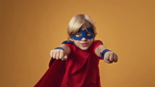 Studio Portrait of Boy in Superhero Costume Flying with Arms Forward