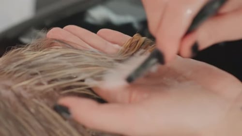Hairdresser Applying Dye to Blonde Hair in Salon