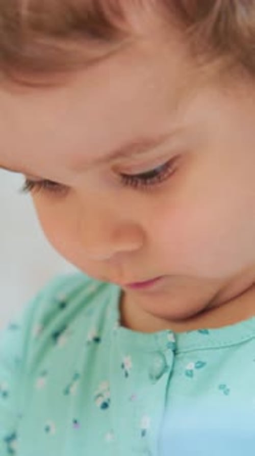 Young Girl Wearing Comfortable Attire Studies Tiny Object with Concentration and Curiosity