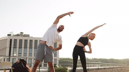Sportpaar macht morgens Gesundheitsgymnastik auf der Dachterrasse des Gebäudes