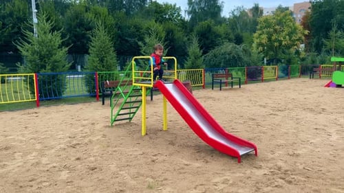 Child Playing on a Red Slide in Park