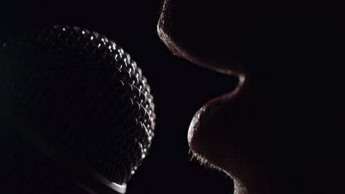 Person Speaking Into Microphone in Dark Close Up