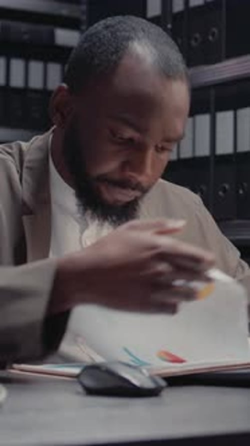 Man Reviews Documents in Workplace Office