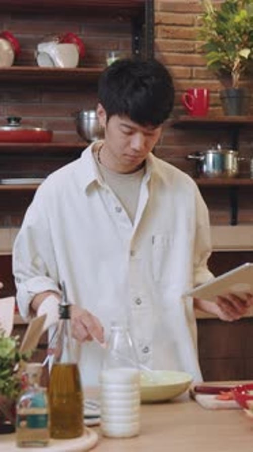 Young Adult Cooking at Home with Tablet Recipe