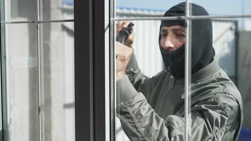 Dieb zerbricht ein Fenster in einem Haus