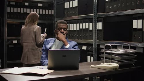 Young Man Working at Desk in File Room