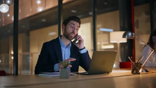 Collègues d'entreprise parlant au téléphone portable dans un espace de travail sombre dans un centre d'affaires