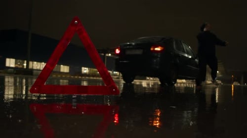 Red Reflective Triangle Signals Roadside Incident and Urgent Need for Help As Person Contacts Road