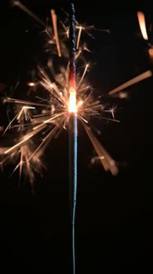 Burning Sparkler Emitting Flashes of Light on Dark Background