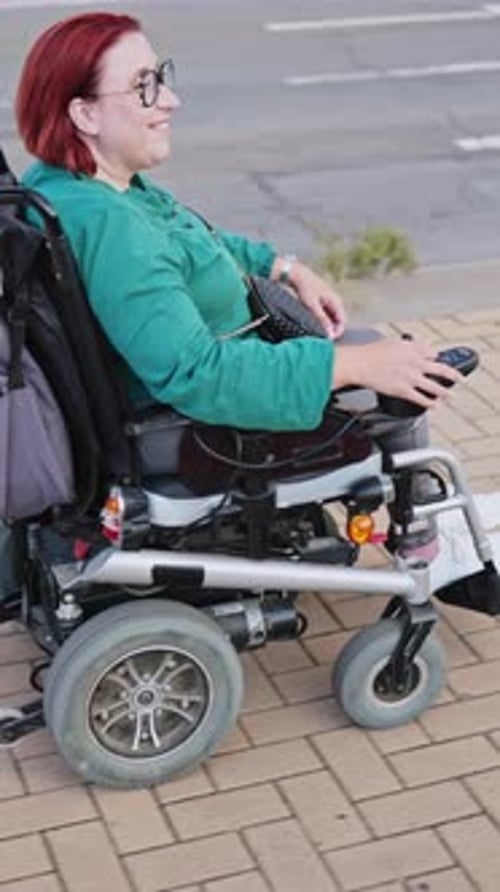 Woman Smiling Riding Electric Wheelchair on Sidewalk
