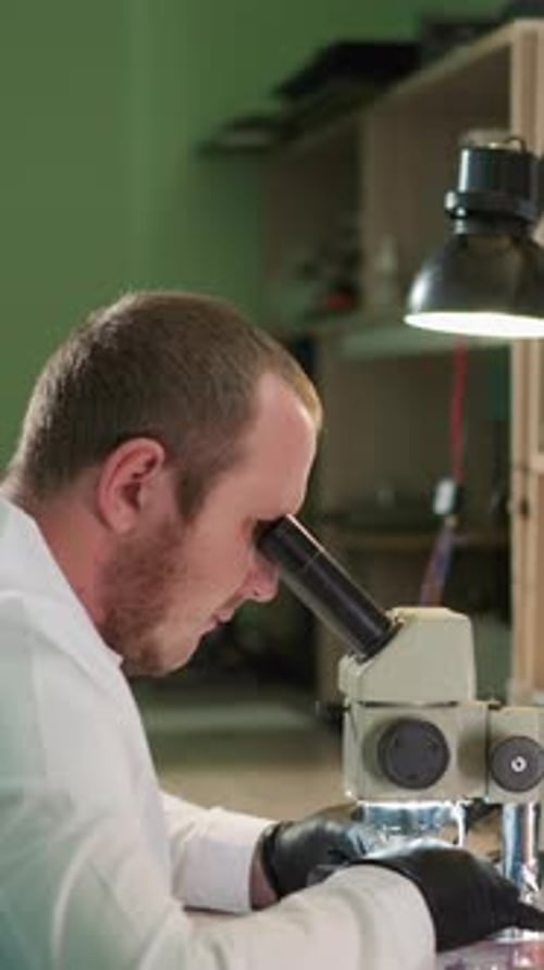 Man Uses Microscope in a Laboratory Setting
