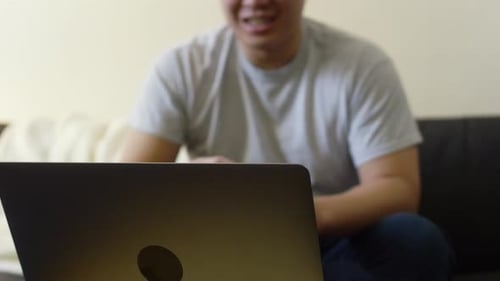 Man Talks Via Laptop on Couch Indoors