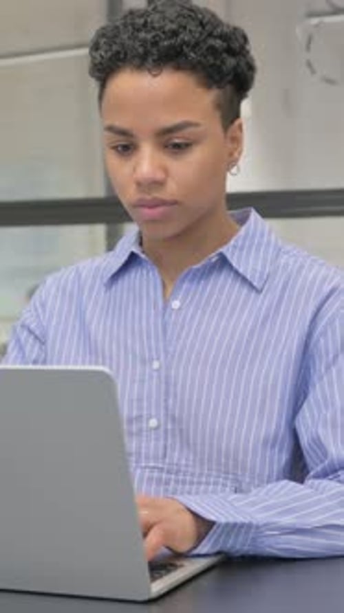 Focused Woman Works on Laptop in Office Setting