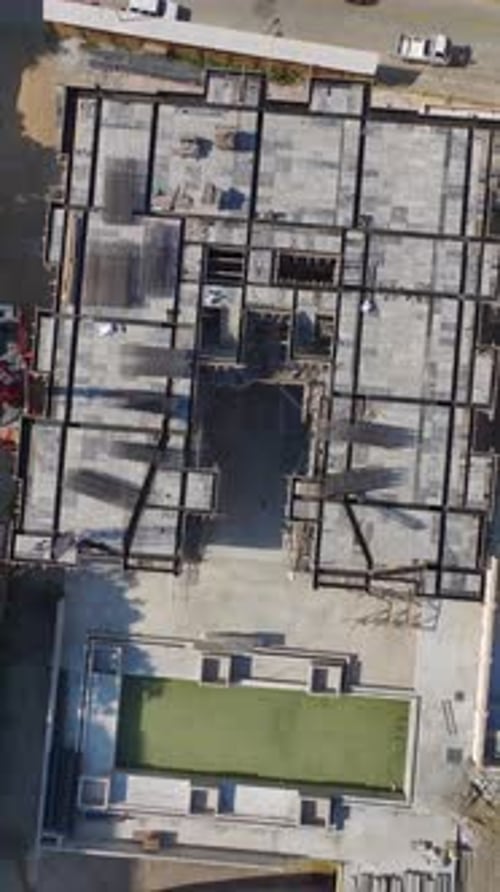 Vídeo vertical: trabajadores en una obra manipulan metales, instalan fachadas y dan forma a piedras