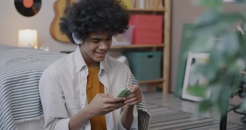 Teen Using Phone with Headphones Indoors