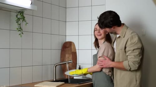 Loving Couple Washing Dishes Together in Bright Kitchen