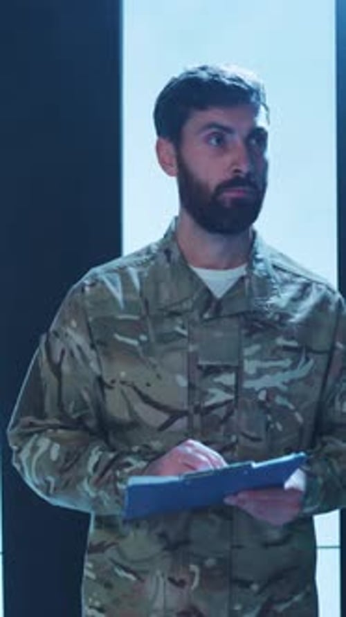 Man in Camouflage Writing on Clipboard