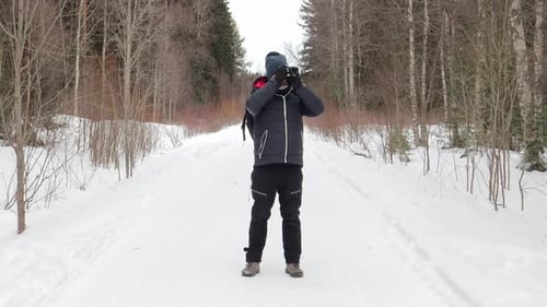 Adventurous Man Photographer Walking in a Snowy Forest in Sweden