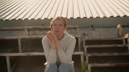 Pensive Woman in Deep Reflection on Rustic Stadium Bleachers