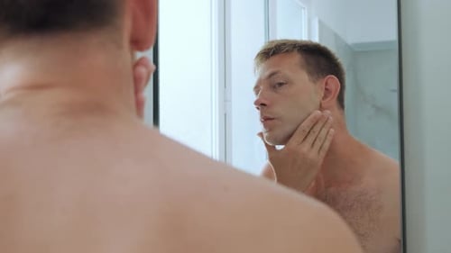Man Applies Shaving Cream in Bathroom Mirror