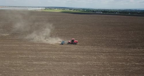Aerial View of Red Tractor Plowing Fertile Field on a Sunny Day