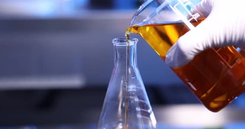Pouring Yellow Liquid into Laboratory Flask in Lab