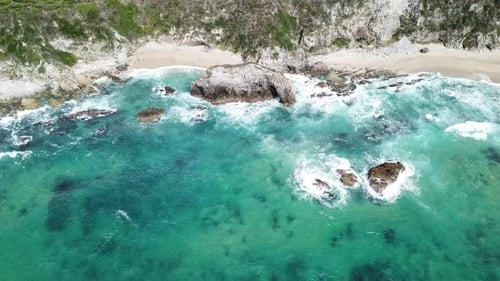 Stunning Aerial View of Turquoise Ocean Waves Crashing on Rocky Coastline