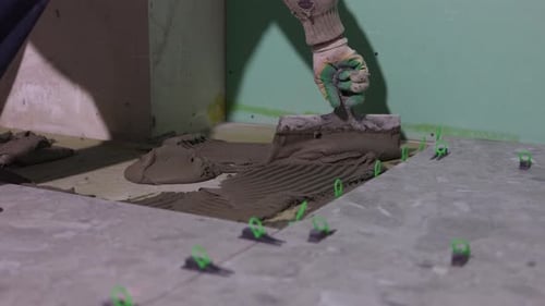 Applying Tile Adhesive with Notched Trowel During Floor Tile Installation