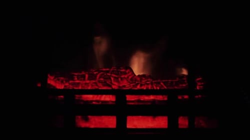 Cheminée chaleureuse et allumée - un feu rougeoyant dans la cheminée en pierre pour se réchauffer la nuit. Tir à mi-distance.