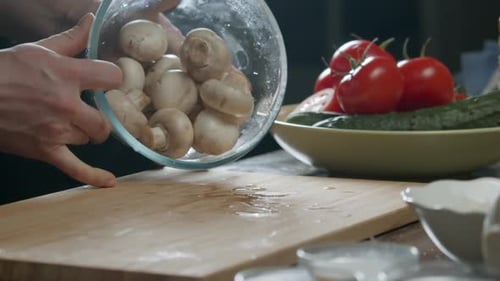 Mushrooms are Falling Onto the Table From a Bowl Against a Black Backdrop