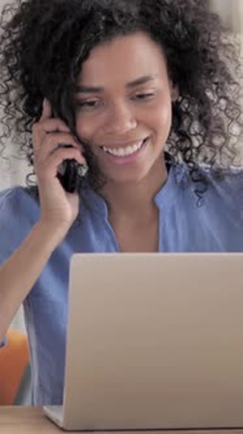 Woman Working on Laptop While Talking on Phone
