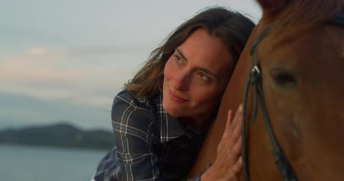 Close Up Portrait of a Beautiful Woman Riding a Horse on Seaside Beach at Sunset. Professional F