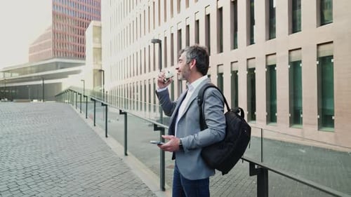 Man Drinks Coffee, Uses Phone in Urban Setting