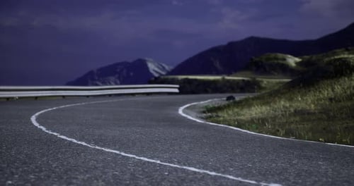 Winding Mountain Road at Night Under a Starry Sky with Distant Peaks